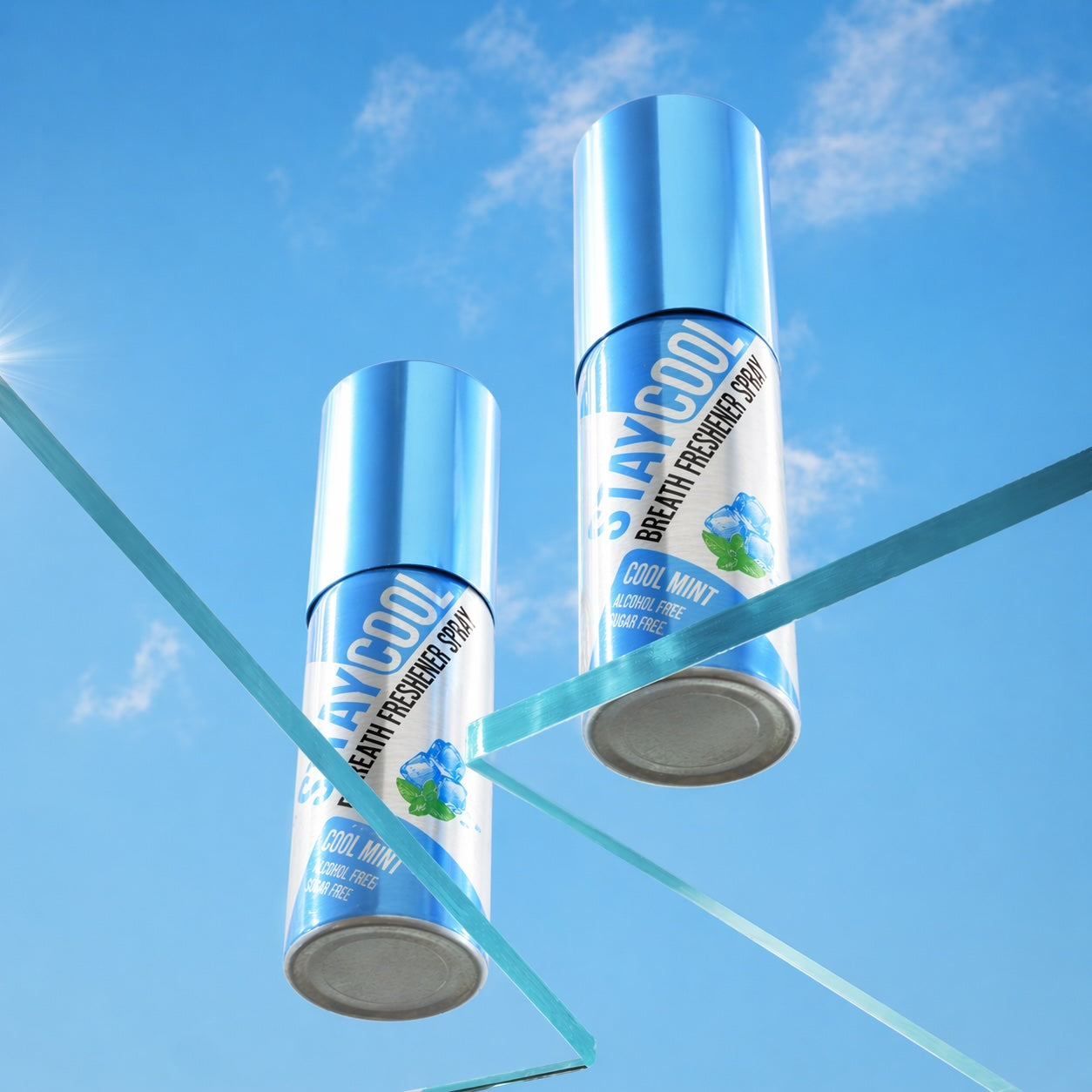 Two cans of 'Stay Cool' breath freshener cool mint flavor spray against a blue sky background.