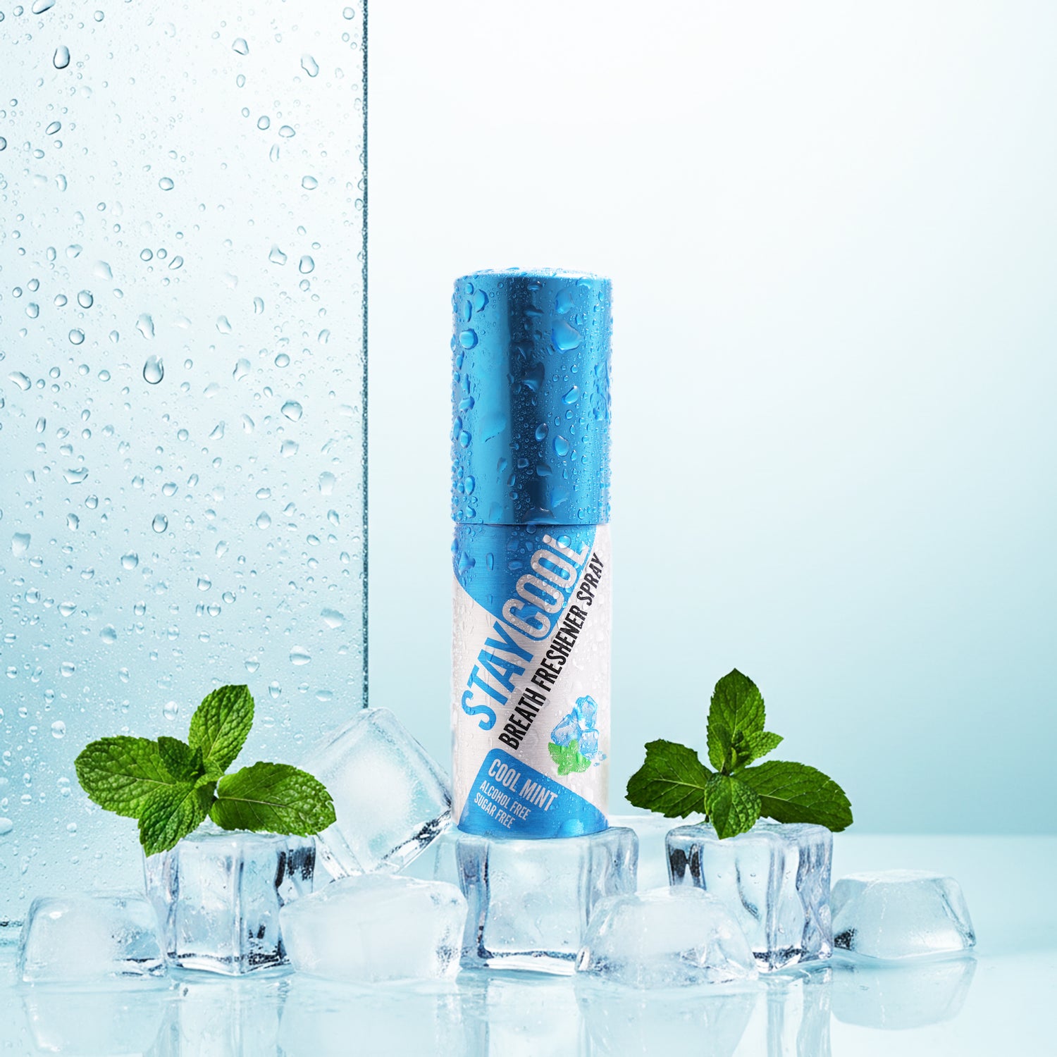 Blue bottle of STAYCOOL breath freshener spray with mint leaves on a light blue background