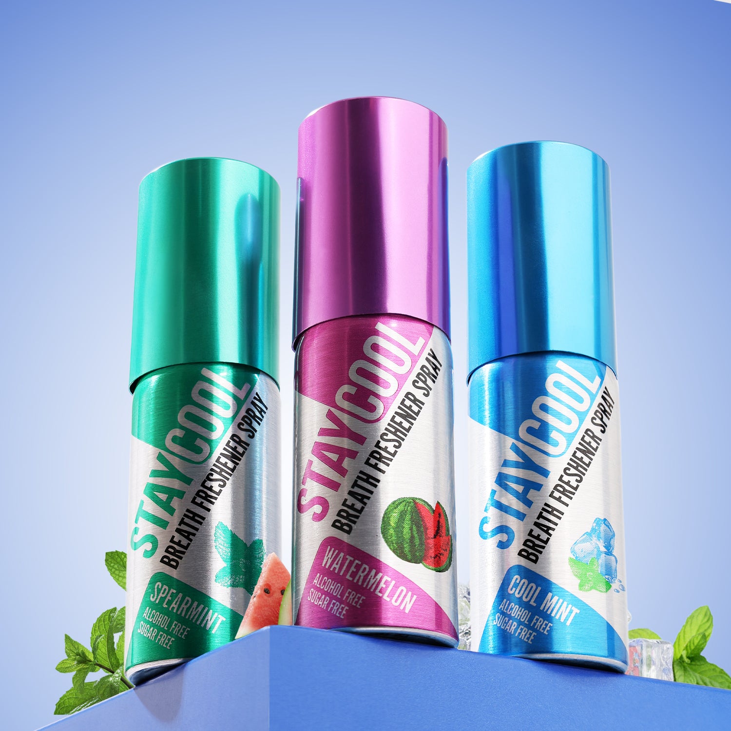 Three Stay Cool breath freshener spray bottles with different flavors on a blue background with Mint leaves and Ice cubes behind the bottles